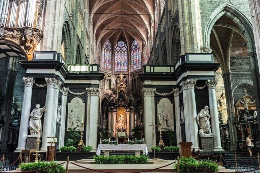 A cathedral interior with Gothic architecture, statues, and a central altar. 4