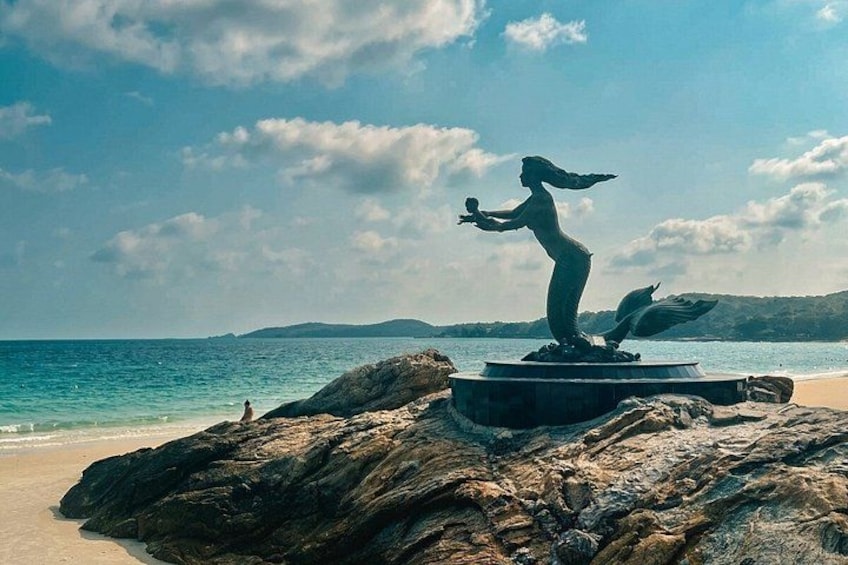 A statue on a rock by the sea with a clear sky. 1