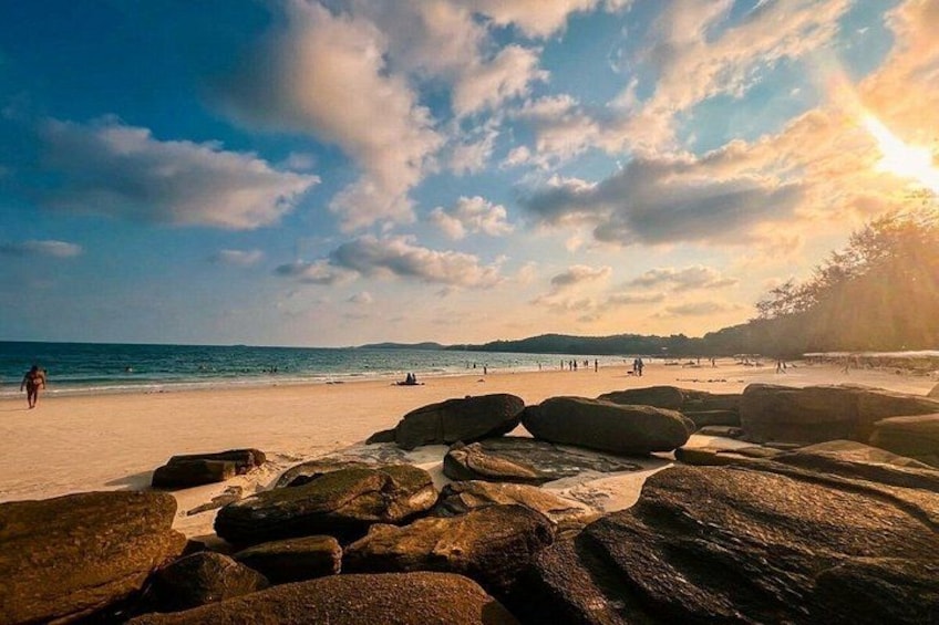 A beach with large rocks in the foreground, a sandy shore, and the ocean in the background. 4