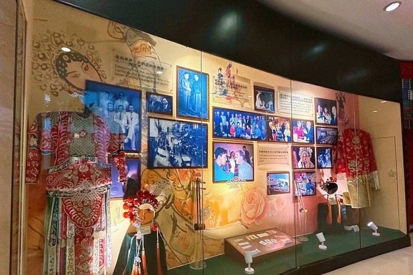 A wall with photographs and traditional clothing. 3