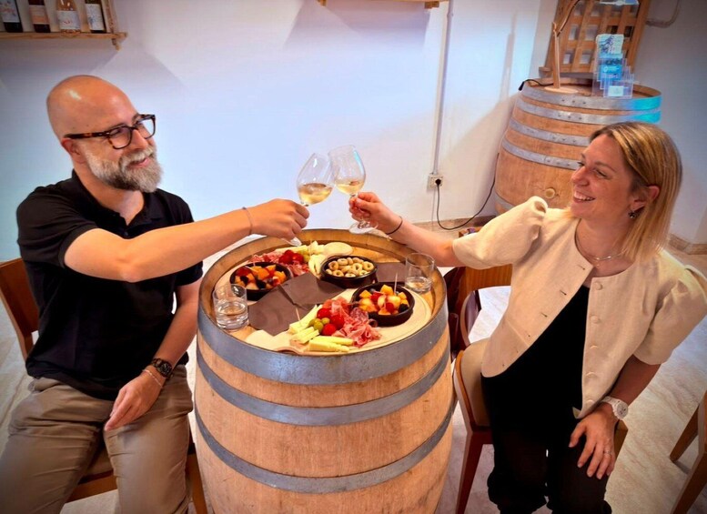 Two people toasting with wine glasses at a table with a charcuterie board. 3