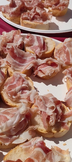 A plate of bread topped with thinly sliced cured meat. 5