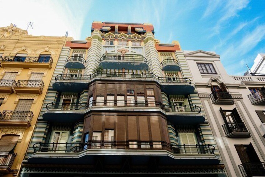A multi-story building with ornate balconies and a distinctive top section. 2