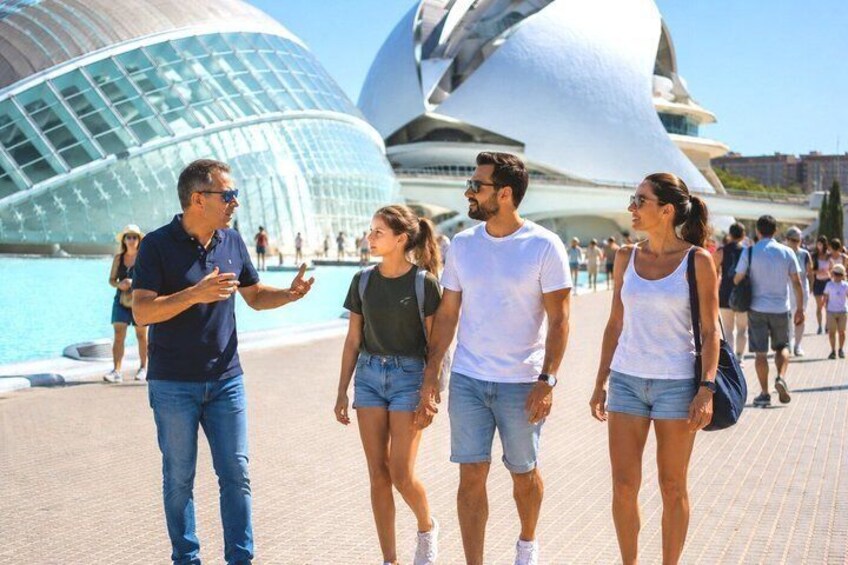 A group of people walking near a modern architectural landmark with a reflective surface. 1
