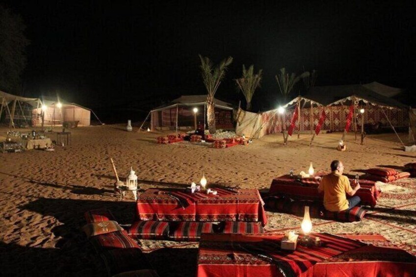 A desert campsite at night with tents, rugs, and candles. 3
