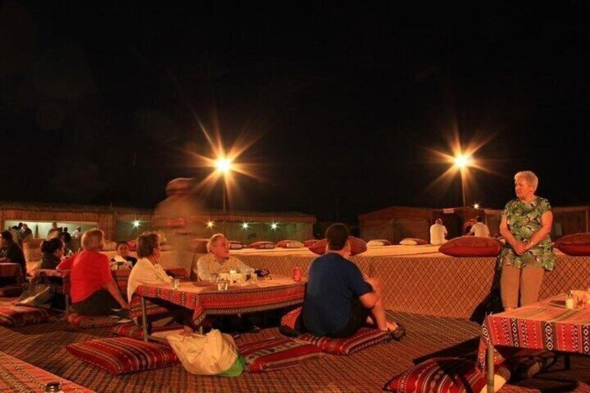 An outdoor dining area with tables and people seated, under bright lights. 2