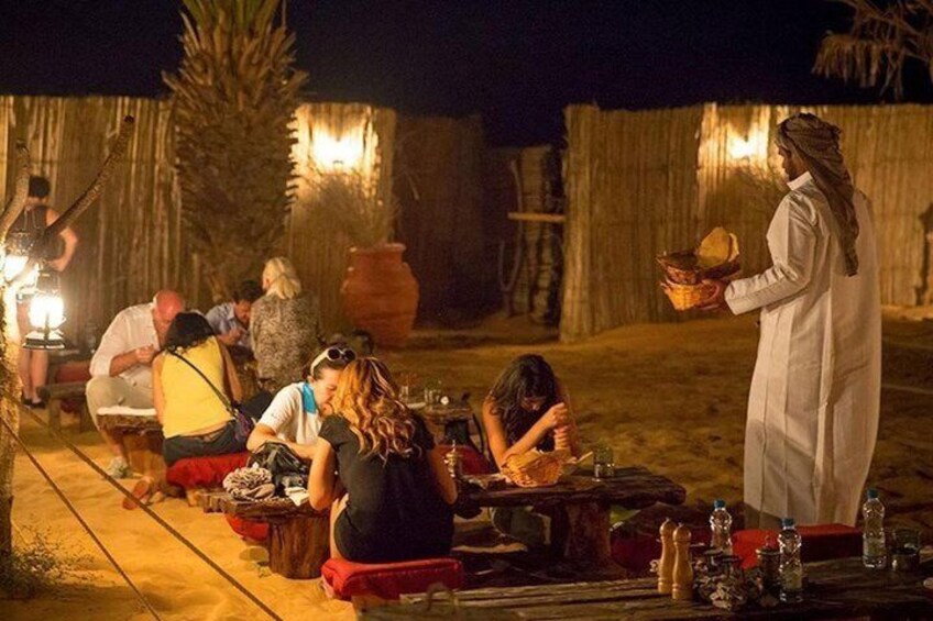 A group of people dining outdoors at night, with a person serving food. 4