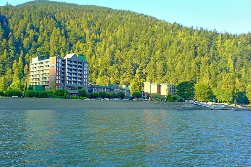 A lakeside building complex with a forested hill in the background. 4