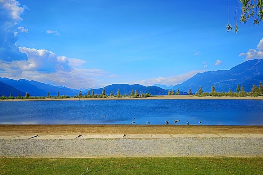A lake with mountains in the background, a grassy shore, and a clear sky. 5