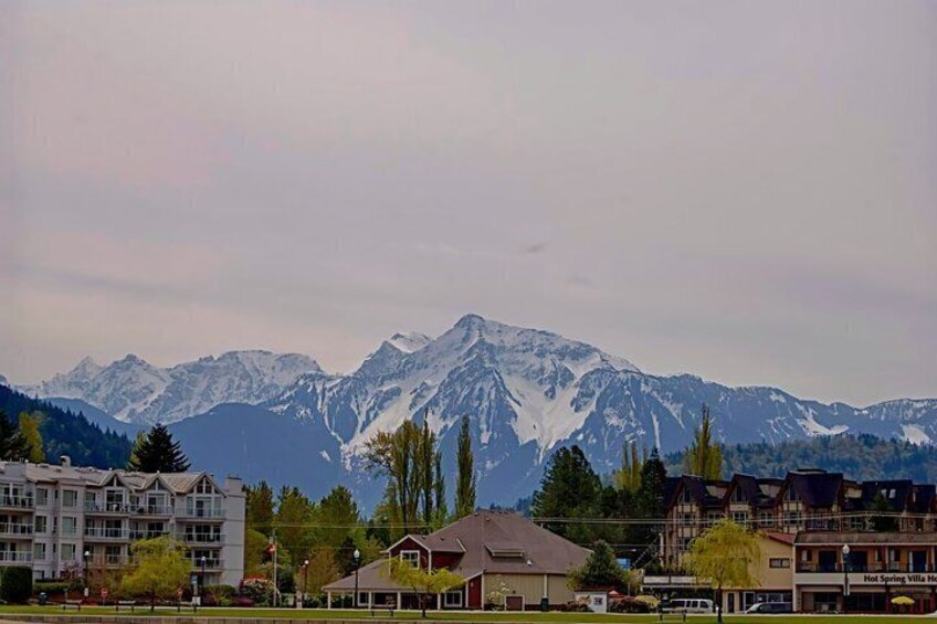 A mountain range with snow-capped peaks, a town with buildings, and a sign for 'Hot Spring Villa Hotel.' 1