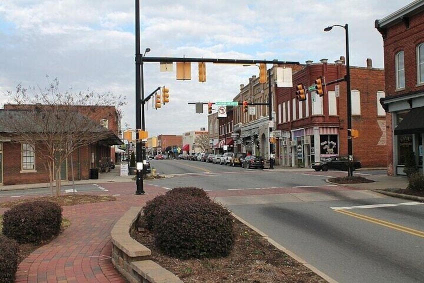 A street with brick buildings, traffic lights, and a clear sky. 1