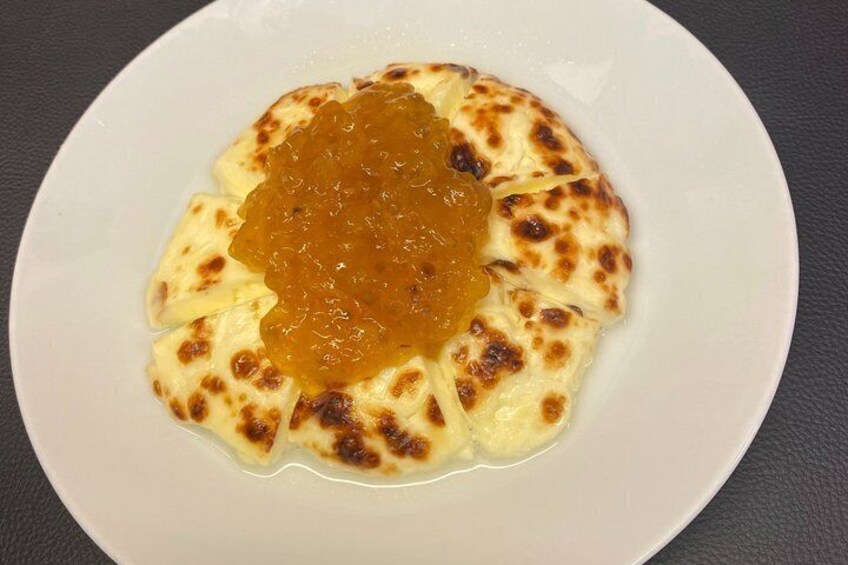 A white plate with a round, golden-brown baked item topped with a dollop of orange jam. 5