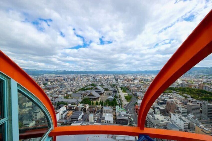 A cityscape viewed from a high vantage point, with a clear sky and a prominent orange structure in the foreground. 4