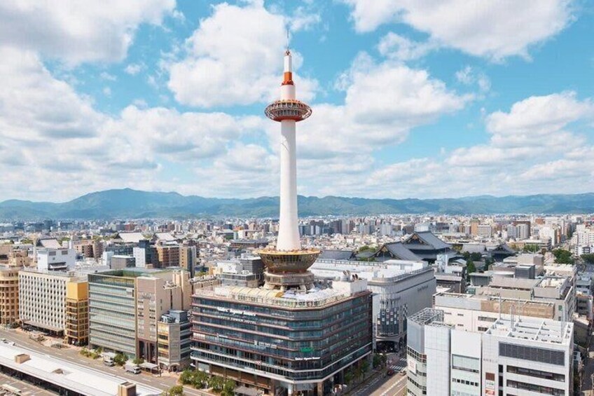 A cityscape with a prominent tower, modern buildings, and a distant mountain range. 2