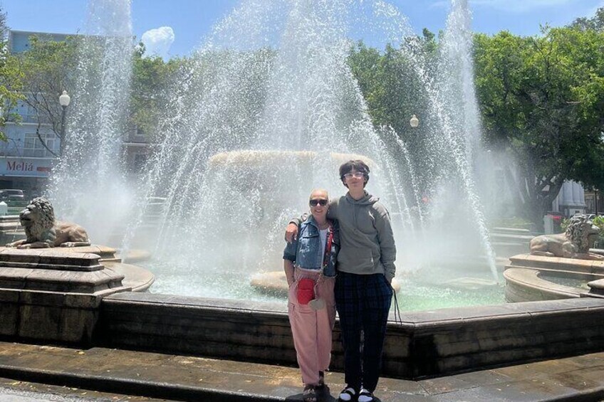 Two people standing in front of a fountain with water jets. 5