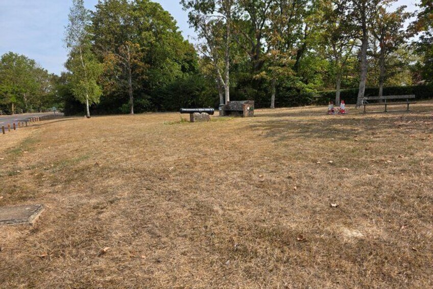A park with a grassy area, a bench, and a signpost. 3