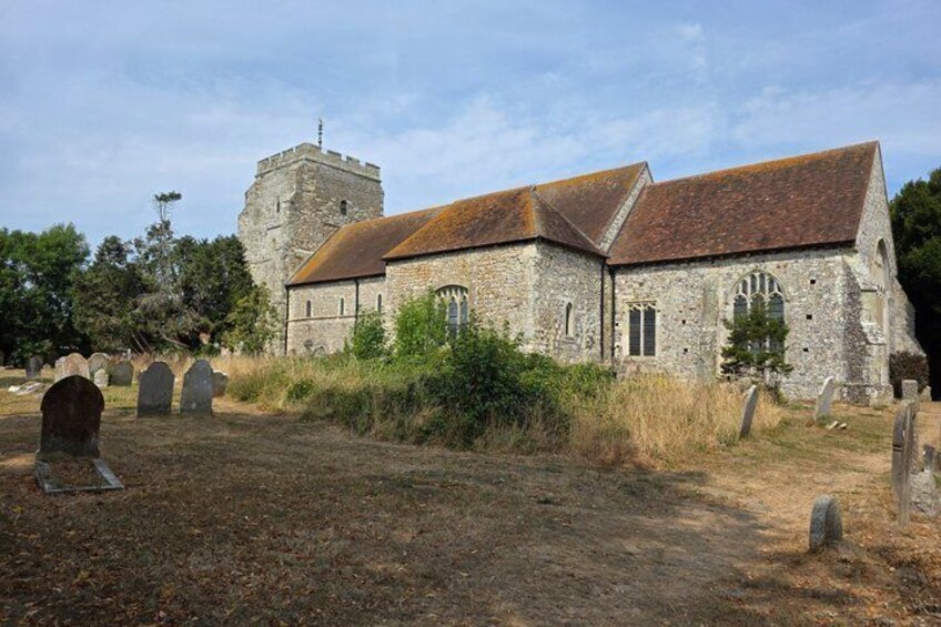 A church with a stone tower and a graveyard with headstones. 4