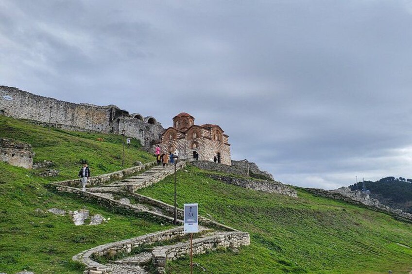 A historical building with a staircase leading up to it, surrounded by grassy hills. 2