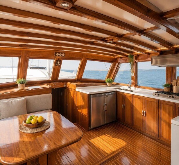 A boat's interior with wooden cabinetry, a dining table with lemons, and a view of the sea. 2