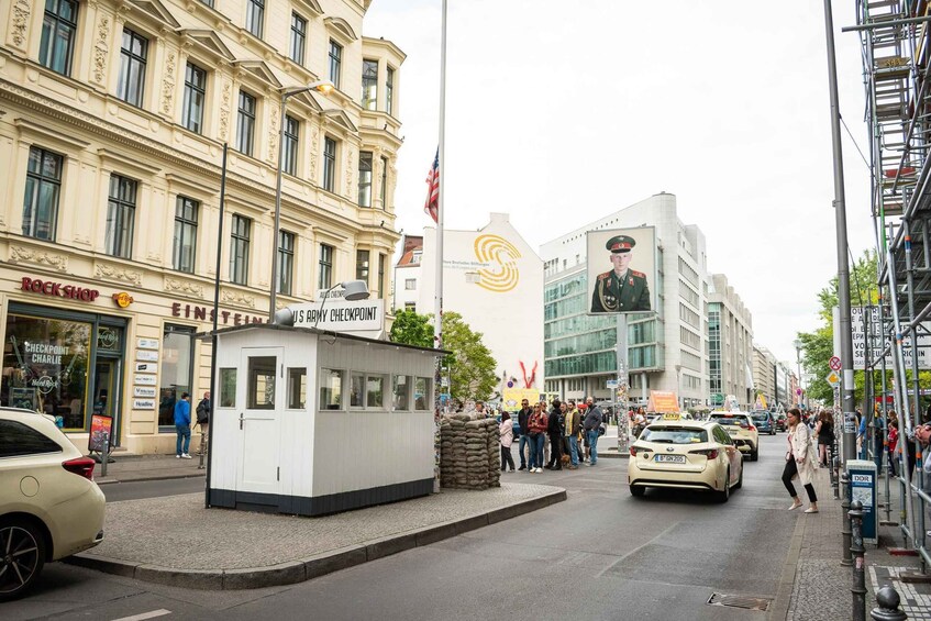 A busy street with a US Army checkpoint, a Rock Shop, and a large building with a mural. 2