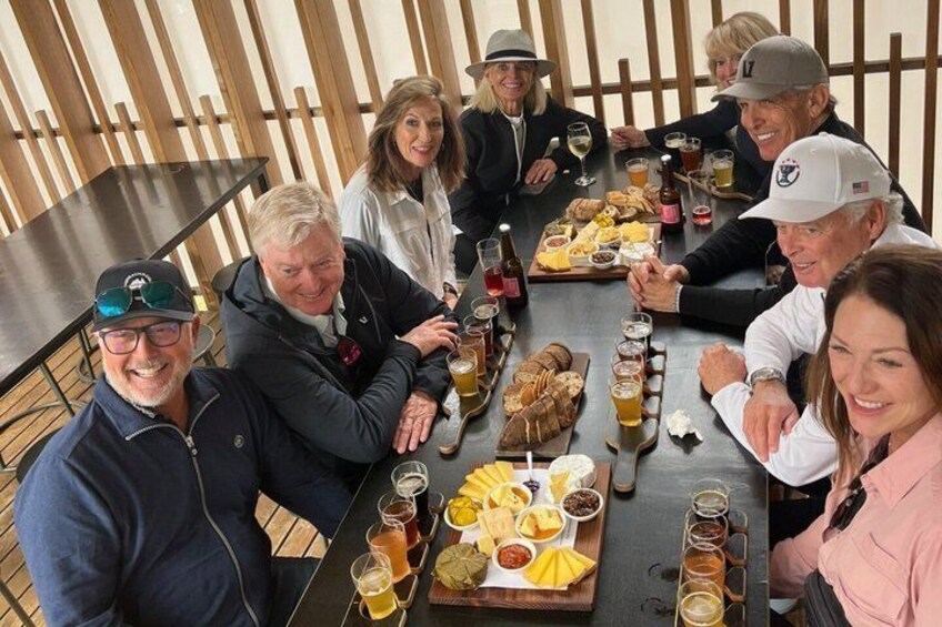 A group of people seated around a table with food and drinks. 2