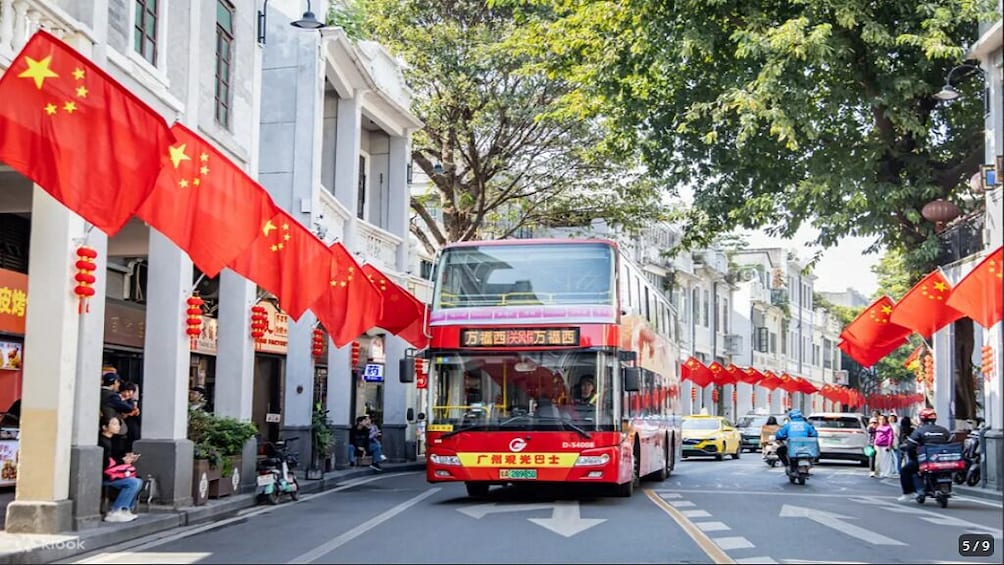 A street lined with red flags, a red bus, and traditional buildings. 1