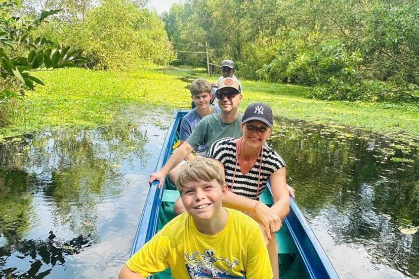 A group of people in a narrow waterway, surrounded by greenery. 4