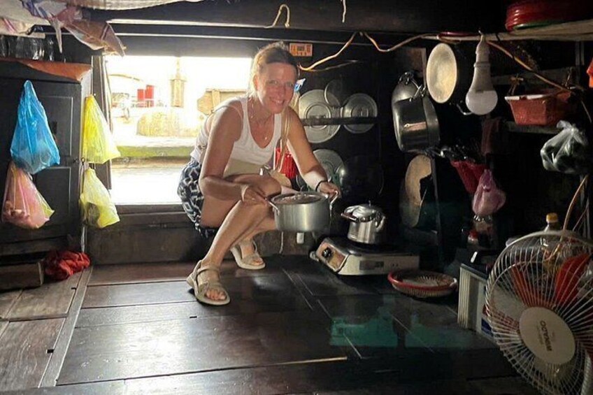 A person cooking in a small, cluttered kitchen with various pots and pans. 5