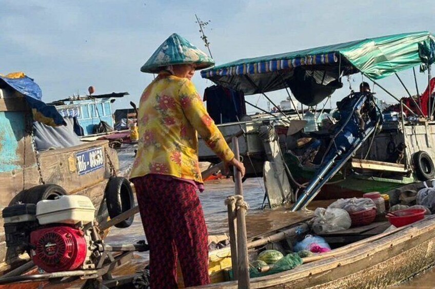 A person in a conical hat working on a boat with various equipment and supplies. 3