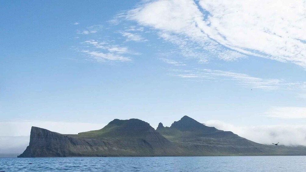 A rugged island with steep cliffs and a calm sea under a partly cloudy sky. 4