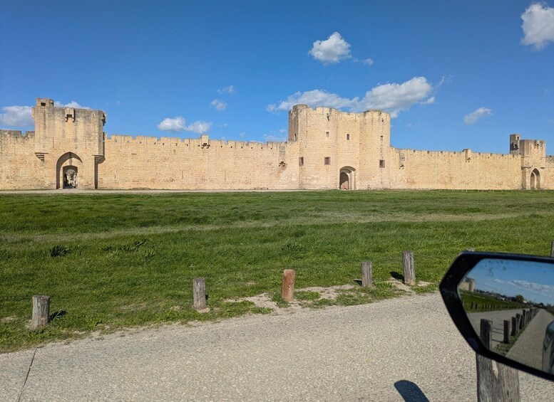 A historic stone castle with arched gateways and battlements, surrounded by a grassy field. 3