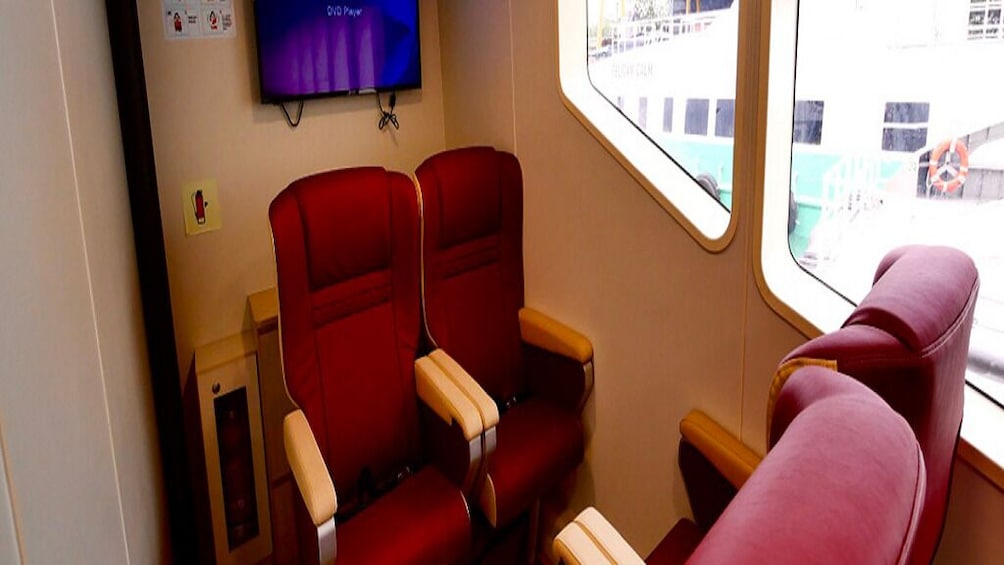 A train carriage with red seats and a television screen displaying '0 to Pay.' 4