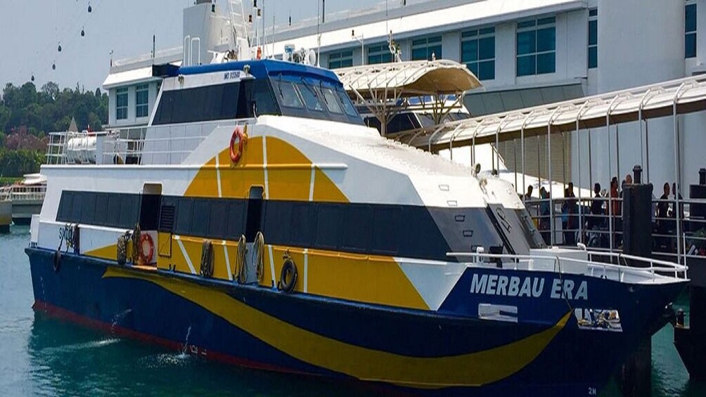 A ferry named 'MERBAU ERA' docked at a pier with a building in the background. 3