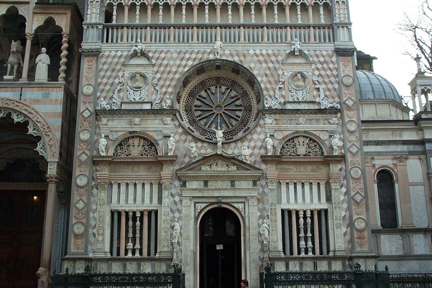 A historic building with intricate geometric patterns, a large central circular window, and statues. 4