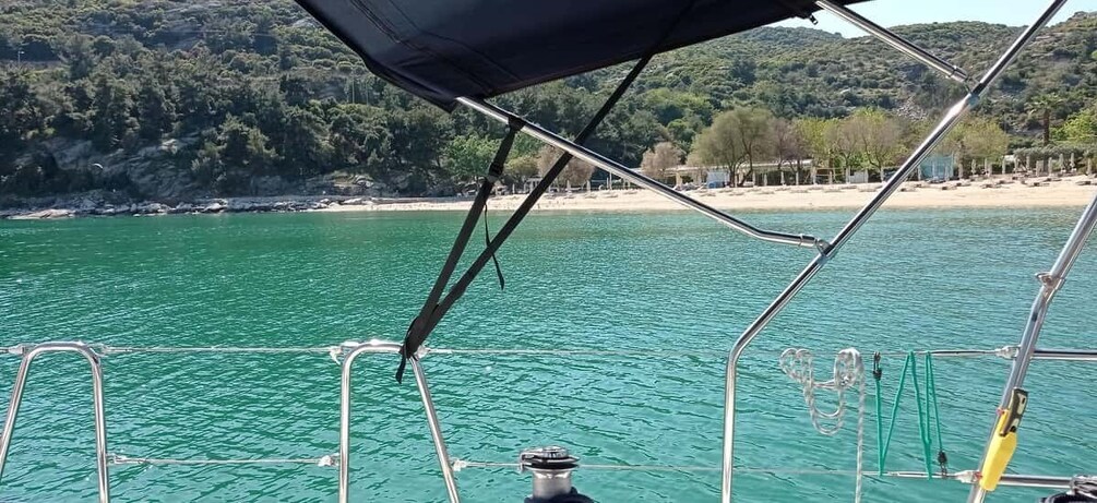 A boat on turquoise water with a beach and forested hills in the background. 5