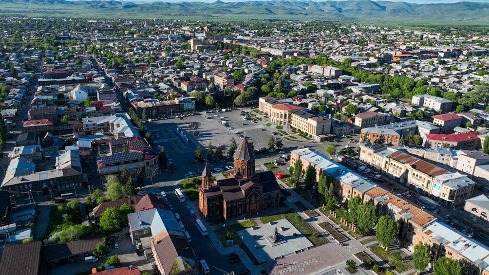 Eine Stadtansicht mit einer markanten Kirche, einem zentralen Platz und umliegenden Wohn- und Geschäftsgebäuden. 4