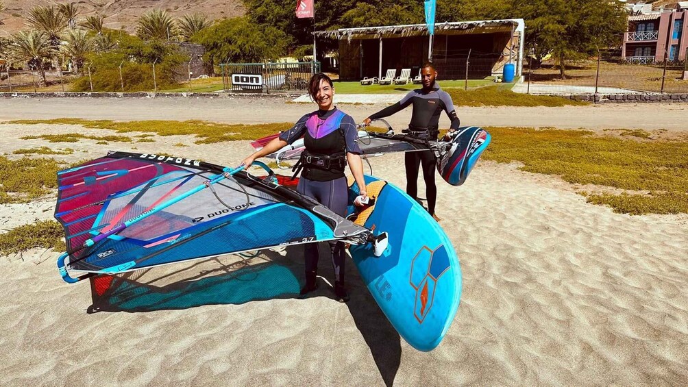 A person with a windsurfing board and a kite on a sandy beach. 3