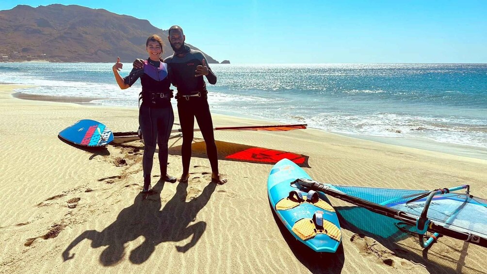 Two people on a beach with surfboards and a paddleboard. 2
