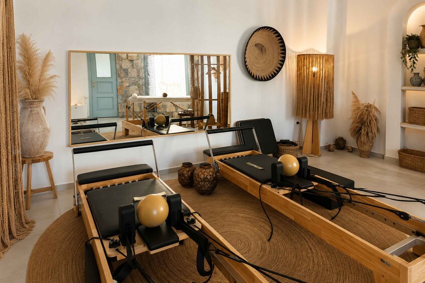A room with two rowing machines, a large mirror, and various decorative items. 1