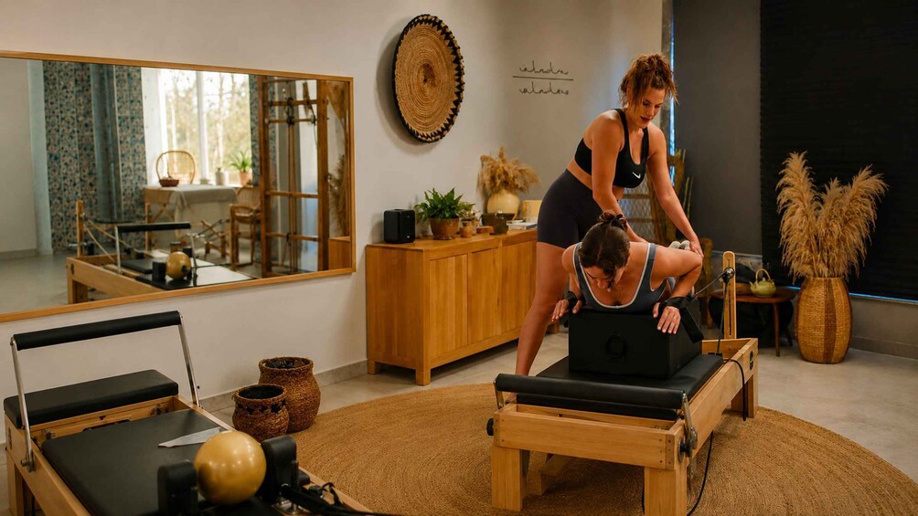 A Pilates studio with a mirrored wall, wooden furniture, and a Pilates reformer machine. 5