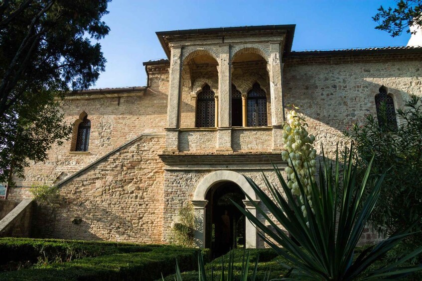 A historic stone building with arched windows and a staircase leading to a door. 5