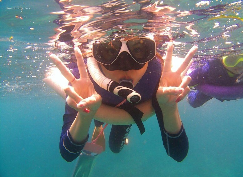 A person underwater making a peace sign with their hands. 2