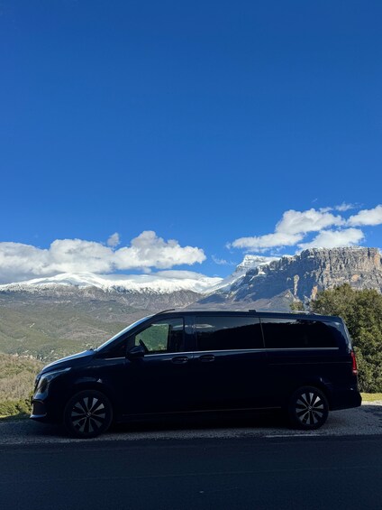 A black minivan parked on a road with a mountainous landscape in the background. 2