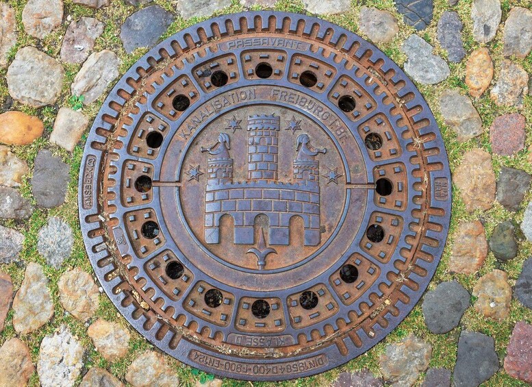 A circular metal plate with a castle and stars, surrounded by stones. 5