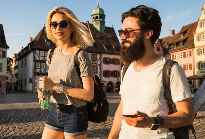 Two people walking on a cobblestone street with traditional half-timbered houses in the background. 5