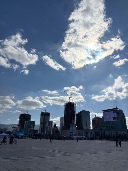A cityscape with a large open square, several buildings, and a statue. 5