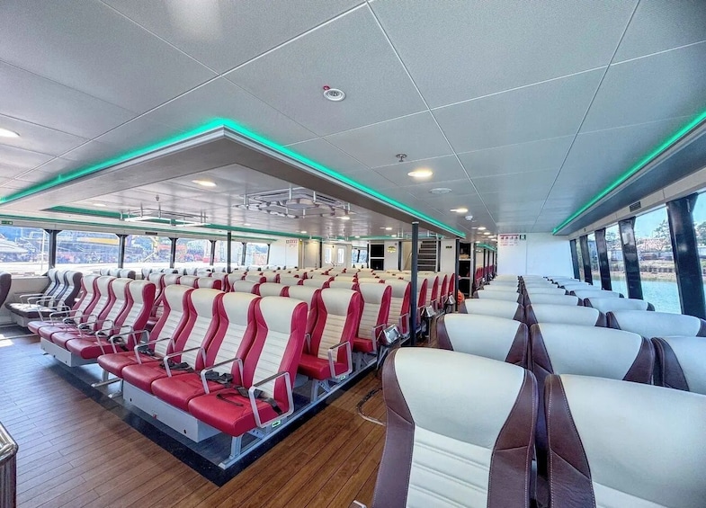 A cruise ship interior with rows of red and white seats, wooden flooring, and green-lit ceiling panels. 3