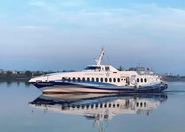 A white and blue yacht named 'Majestic Fast Ferry' with the number 'WAVEMASTER 3' on its bow, docked on calm water with a clear sky in the background. 1