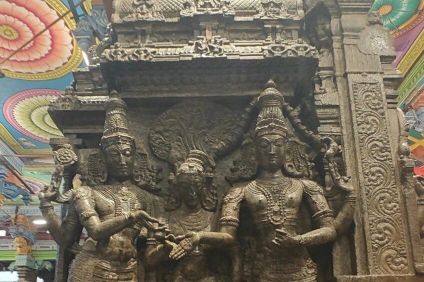 A stone sculpture of deities with intricate carvings, set against a colorful ceiling. 4