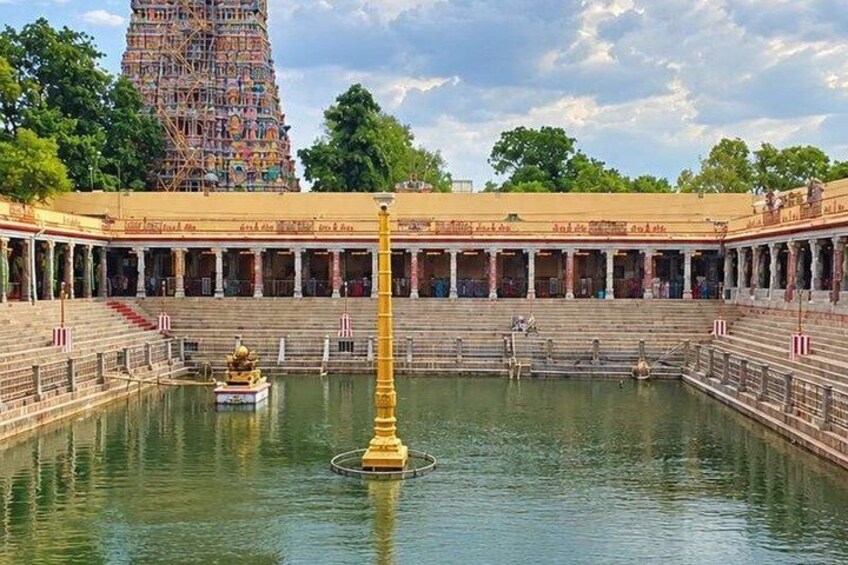 A temple with a large water tank, steps leading up to it, and a tall tower in the background. 5